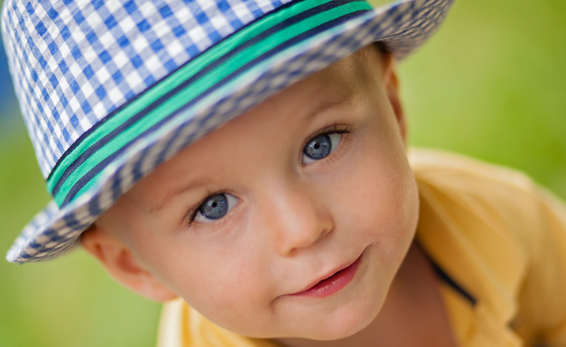 beautiful male child with blue and white hat and blue eyes looking up at camera
