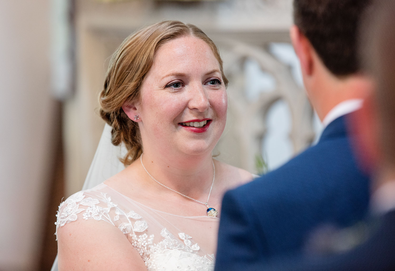 Beautiful smiling bride with red lipstick making eye contact with the groom